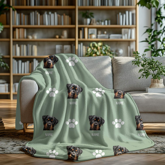 Green blanket with dog faces and paw prints on a couch in a living room setting.