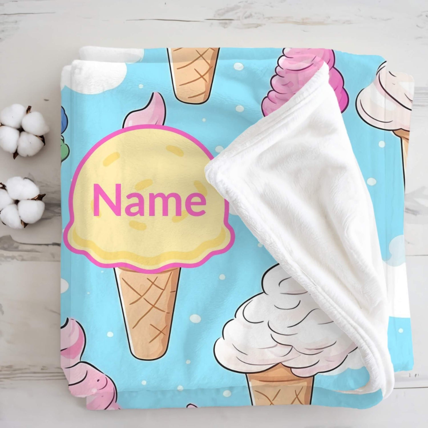 a custom blanket with ice cream pattern and text "Name" on it,  the blanket is on a wood floor 