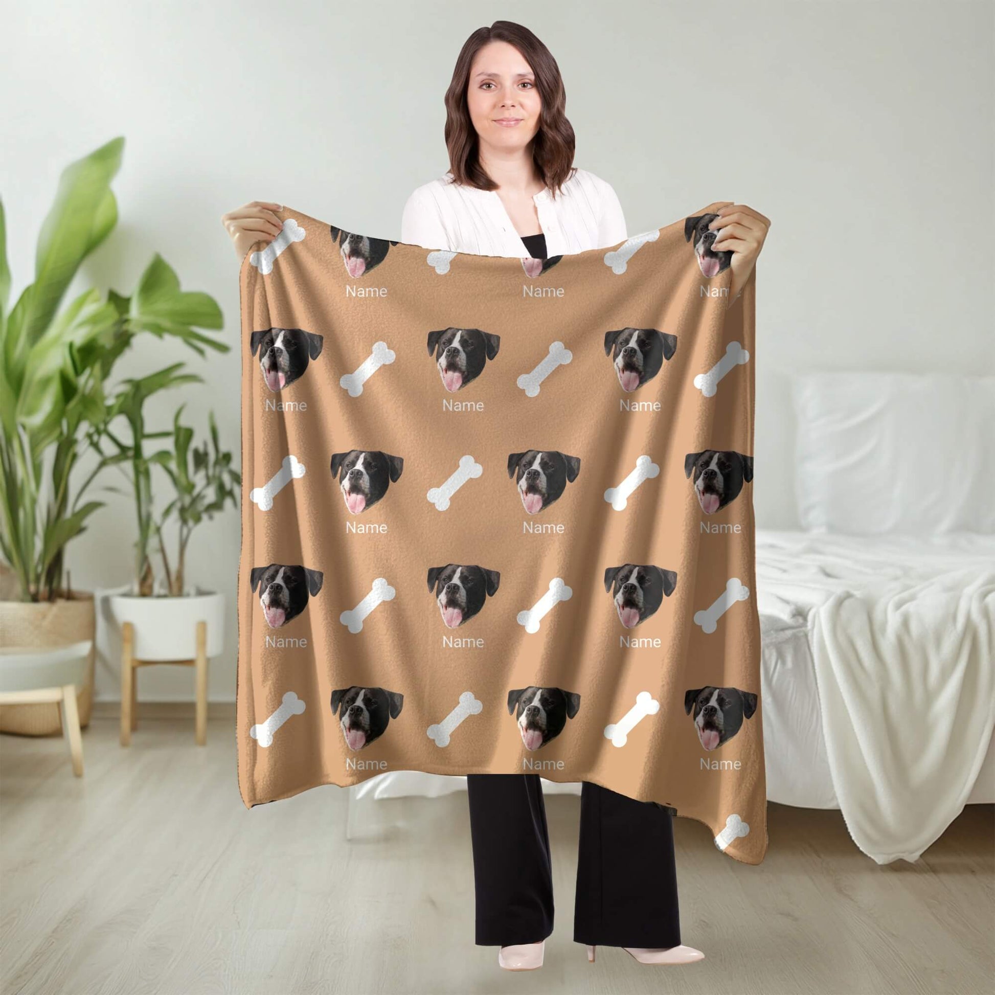Person holding a brown blanket with dog faces and bones pattern in a room.