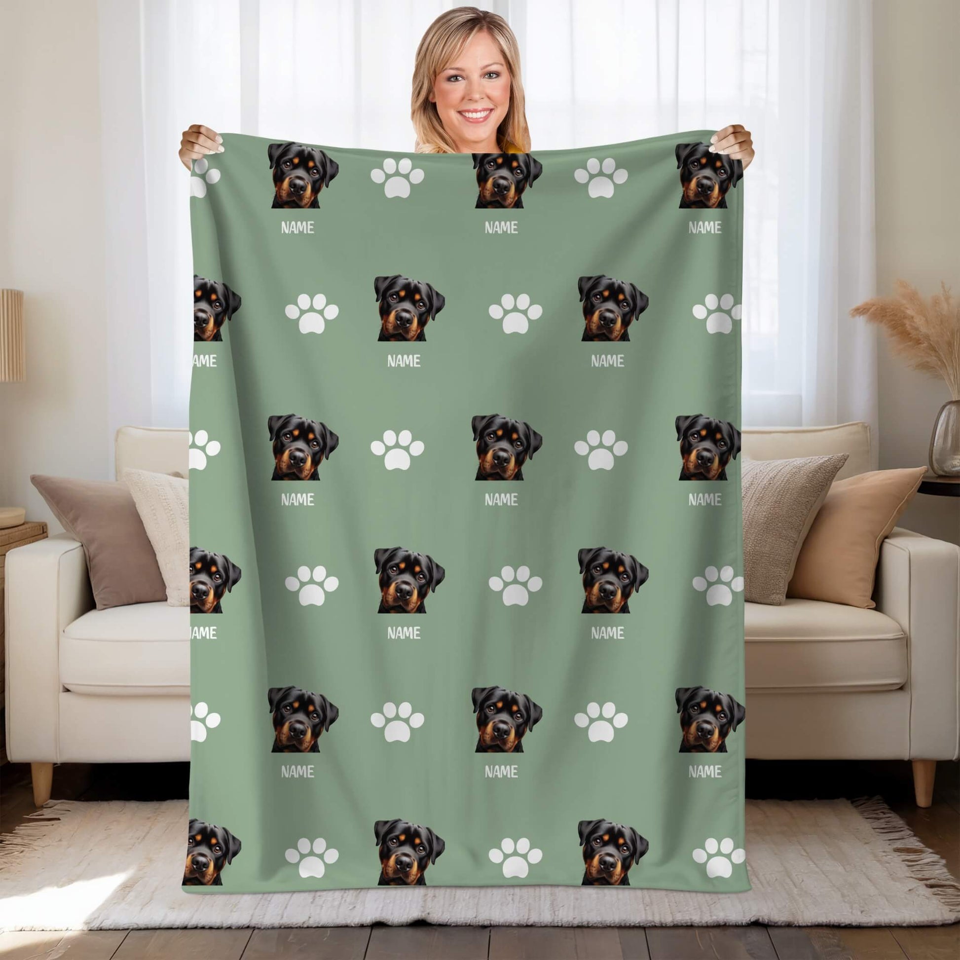 Person holding a green blanket with Rottweiler pattern in a living room.
