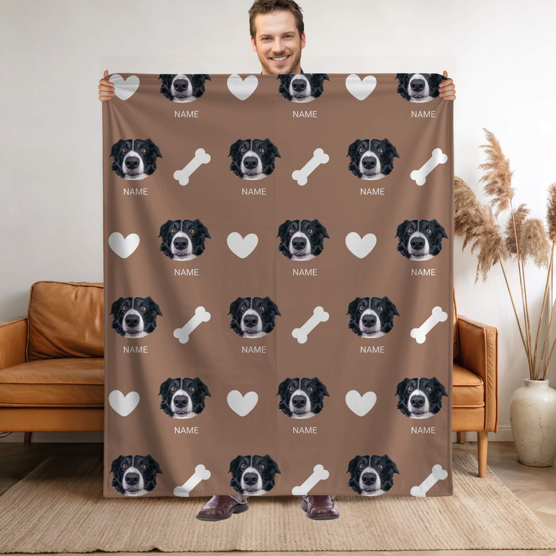 Person holding a blanket with a pattern of a dog's face and bones on a brown background.