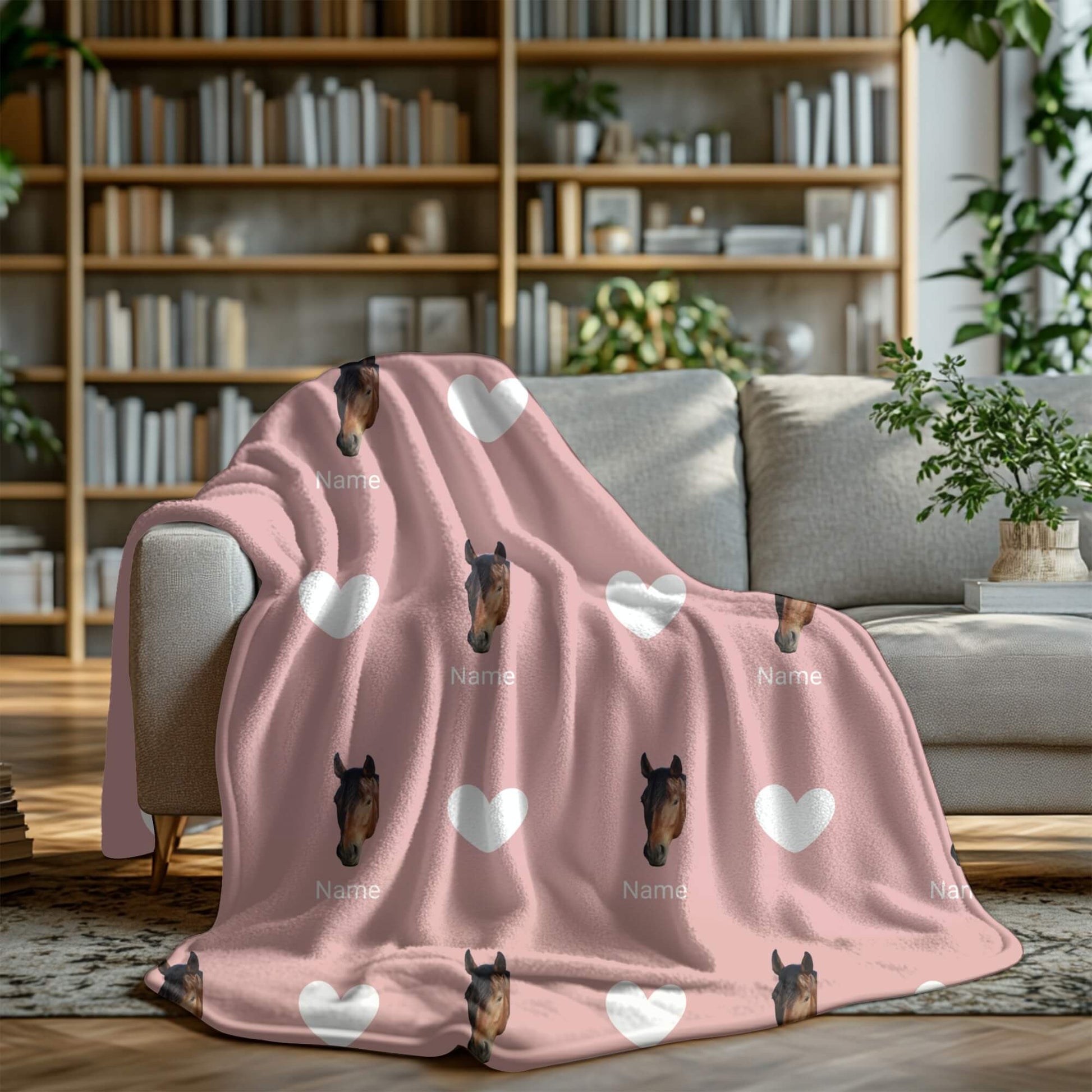 Pink blanket with horse faces and hearts on a gray sofa in a cozy living room.