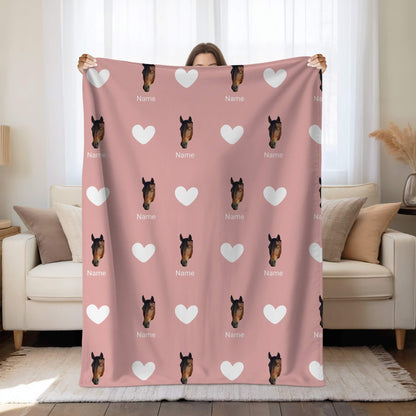 Person holding a pink blanket with horse faces and hearts pattern in a living room.