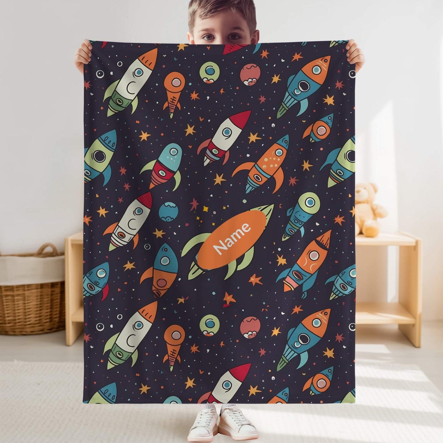 Child holding a colorful space-themed blanket with rockets and planets