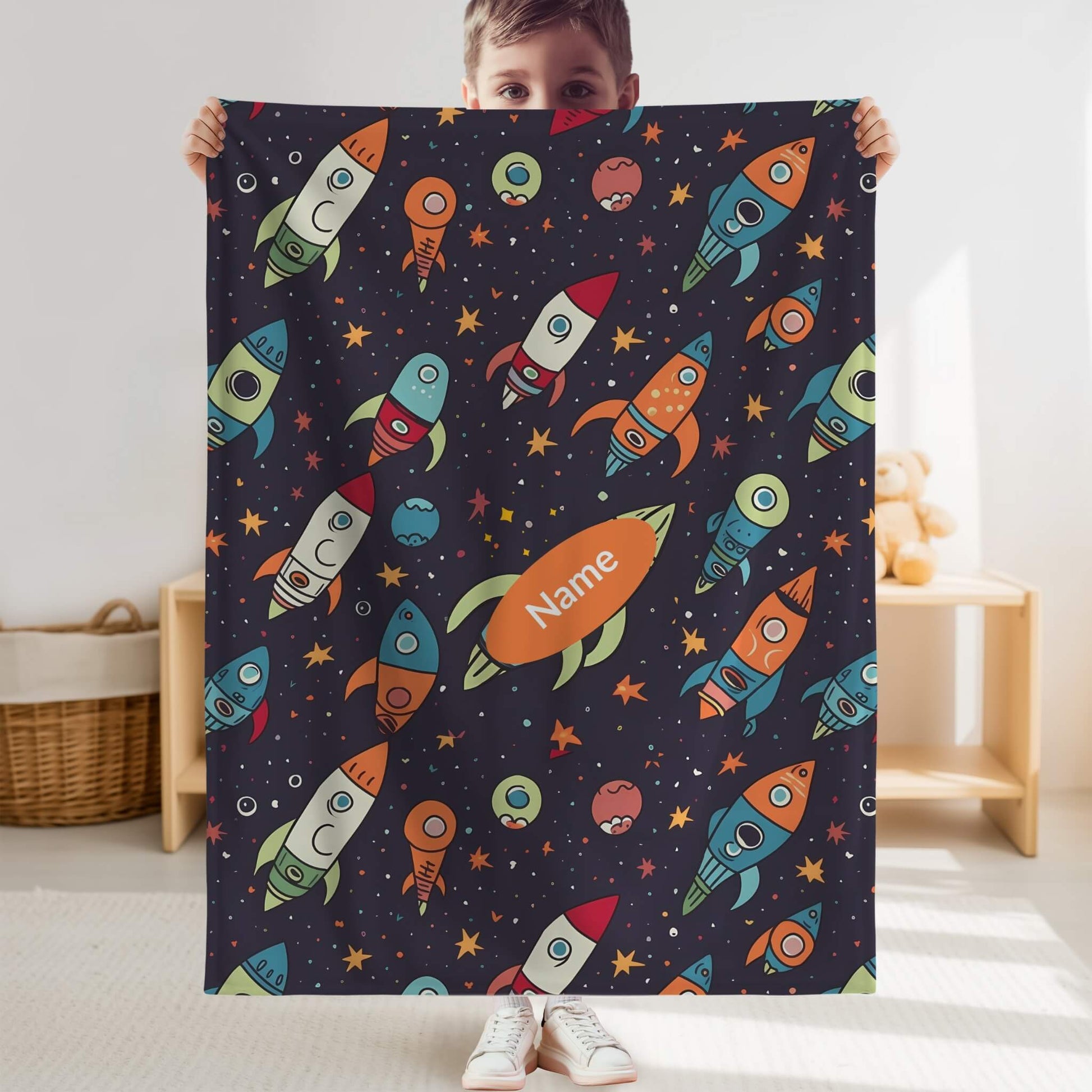 Child holding a colorful space-themed blanket with rockets and planets