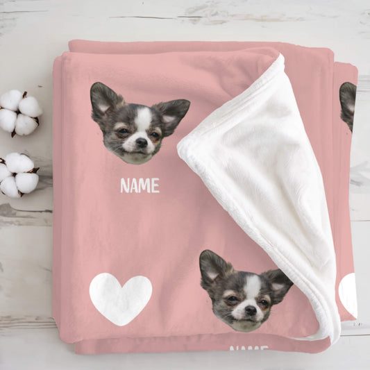 Pink blanket with a dog's face and 'NAME' text, surrounded by cotton bolls on a wooden surface.