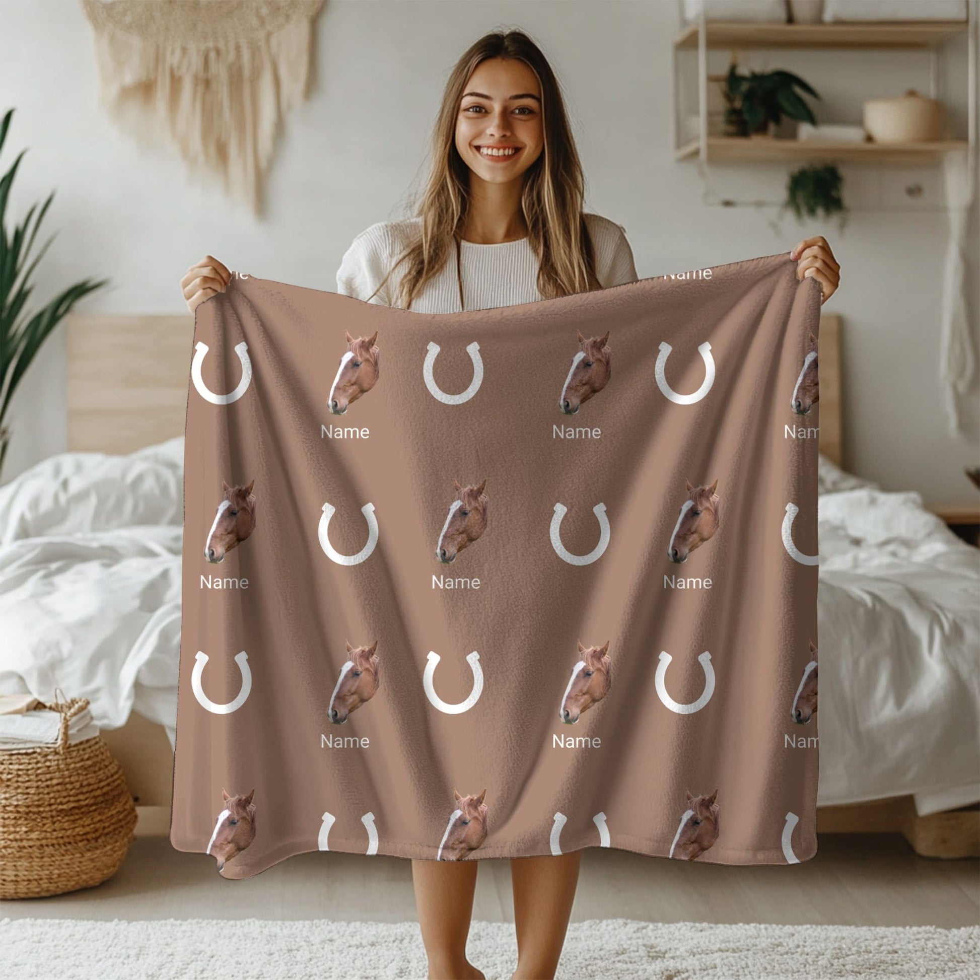 Woman holding a brown blanket with horse patterns and text in a bedroom setting