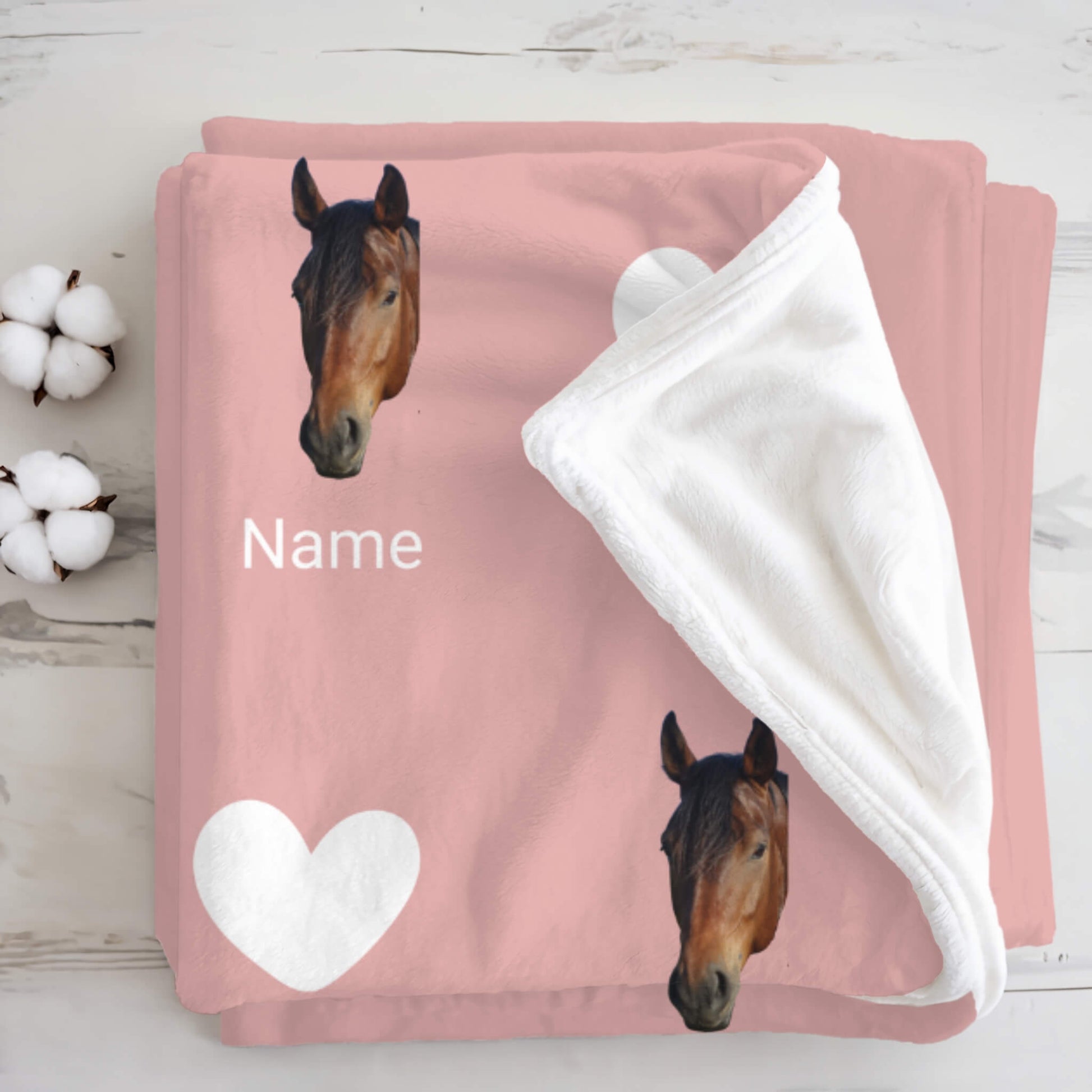 Pink blanket with horse designs and a heart on a wooden surface.