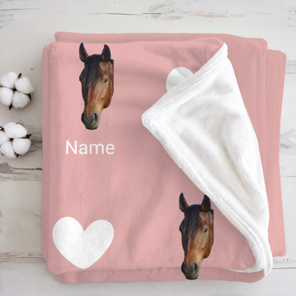 Pink blanket with horse designs and a heart on a wooden surface.